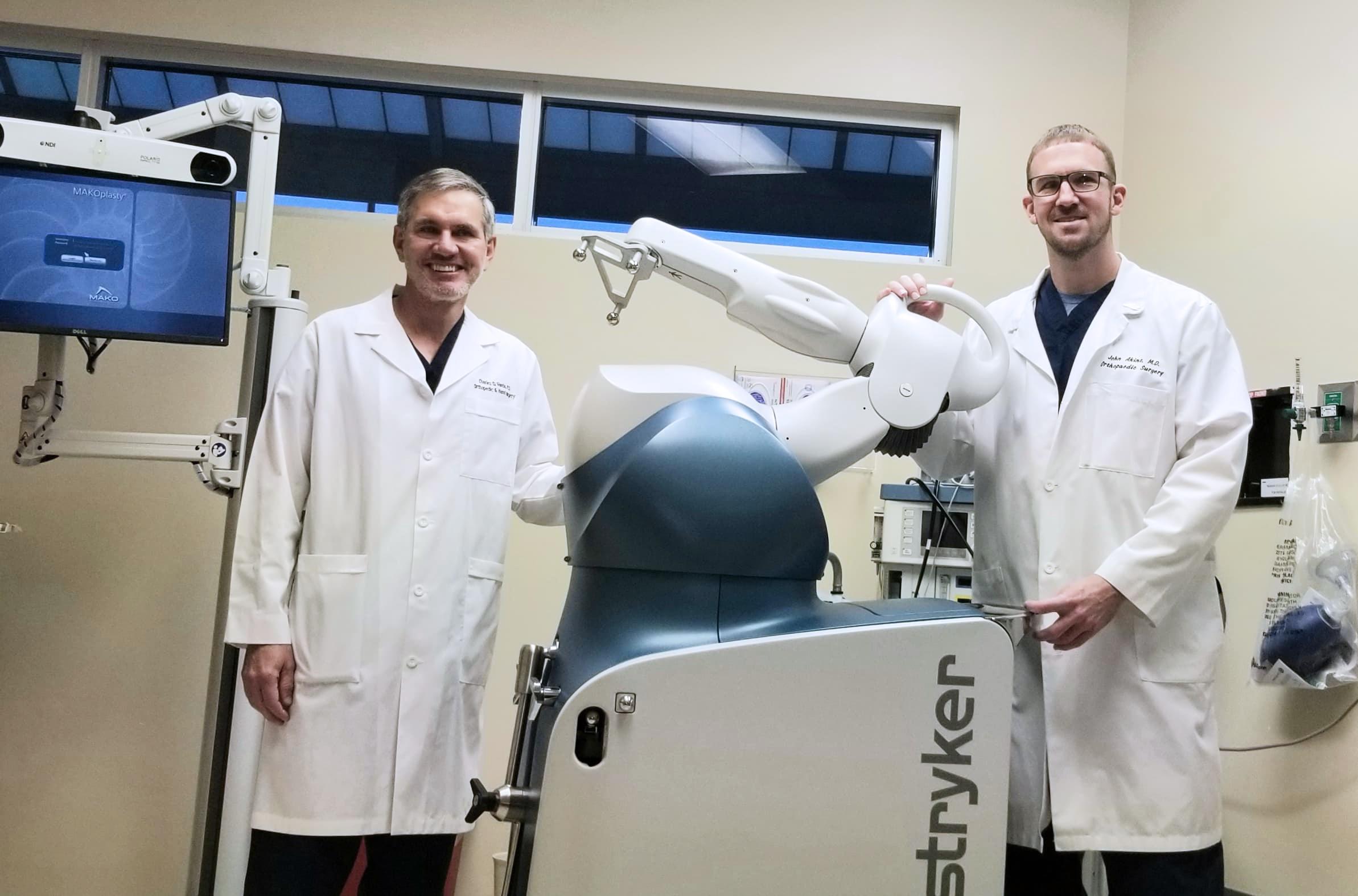 Dr. Varela and Dr. Akins standing by the Mako Robotic System